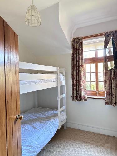 a bedroom with two bunk beds and a window at Bwythyn Ebrill, April Cottage in Betws-y-coed