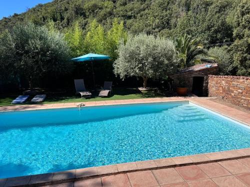 une piscine dans une cour avec un parasol dans l'établissement Villa paisible et relaxante avec piscine a la campagne, à Collobrières