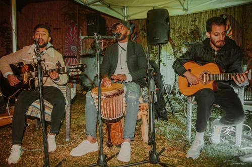a group of three men sitting in chairs playing guitars at harmony surf lodge in Taghazout
