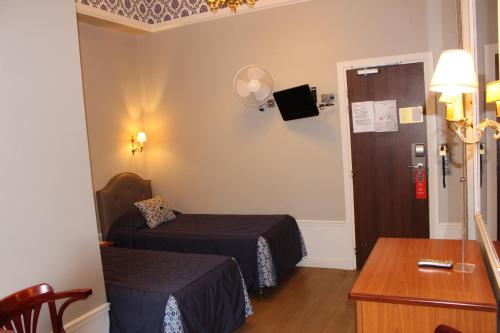 a small room with two beds and a table at Hotel Montpensier in Paris