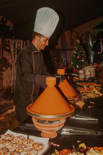 a man in a chefs hat preparing food on a table at harmony surf lodge in Taghazout