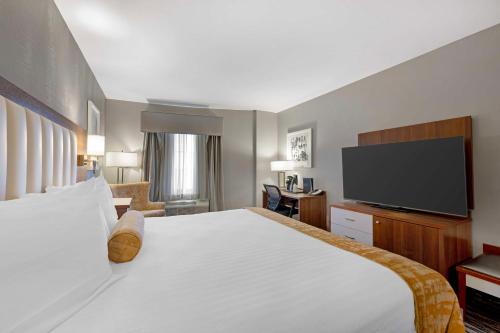 a hotel room with a bed and a flat screen tv at Best Western On The Avenue in Buffalo