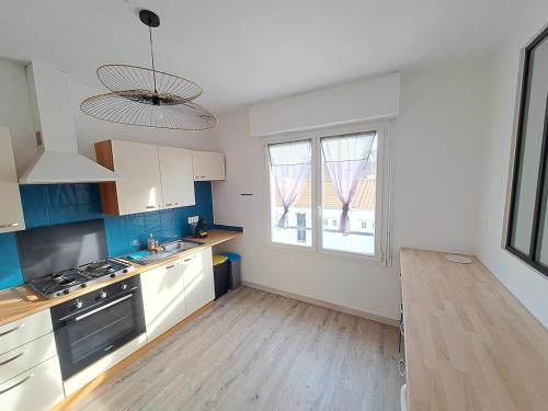 une cuisine avec des placards blancs et une grande fenêtre dans l'établissement L'appart en hyper centre, à Challans