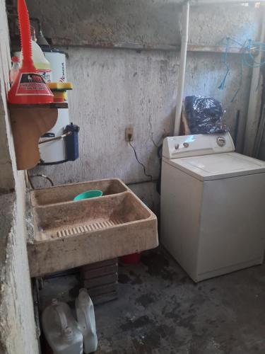 a dirty kitchen with a sink and a washing machine at Casa de tres habitaciones por infonavit constituyentes in Uruapan del Progreso