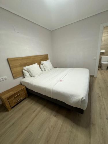 a bedroom with a white bed and a wooden floor at Hotel Boutique Albussanluis in Muriedas