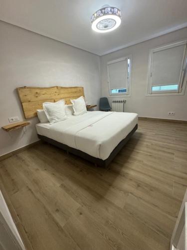 a bedroom with a large white bed and wooden floors at Hotel Boutique Albussanluis in Muriedas