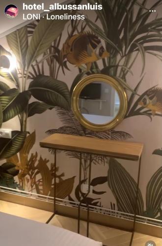a mirror on a table with a mural of plants at Hotel Boutique Albussanluis in Muriedas