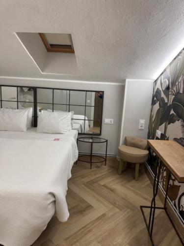 a bedroom with a large white bed and a table at Hotel Boutique Albussanluis in Muriedas