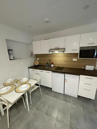 une cuisine avec des armoires blanches et une table et des chaises dans l'établissement Appartement T2, à Saint-Lys
