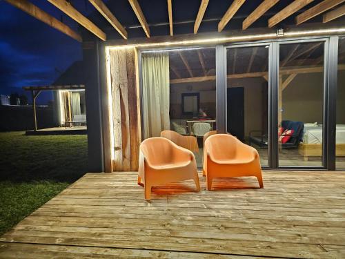 three orange chairs sitting on a wooden deck at Chata w Bieszczadzie apartamenty i domki z basenem Bieszczady in Polańczyk
