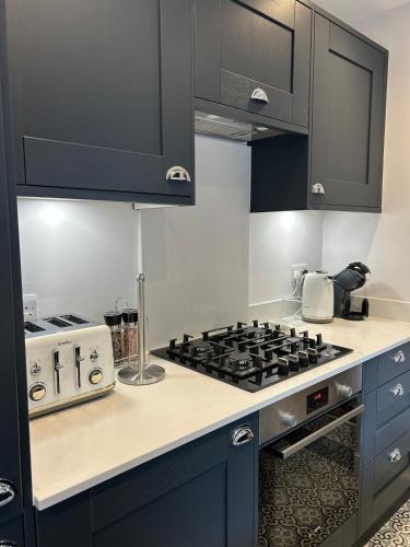 a kitchen with black cabinets and a stove top oven at Kings reach eton, great location in Eton