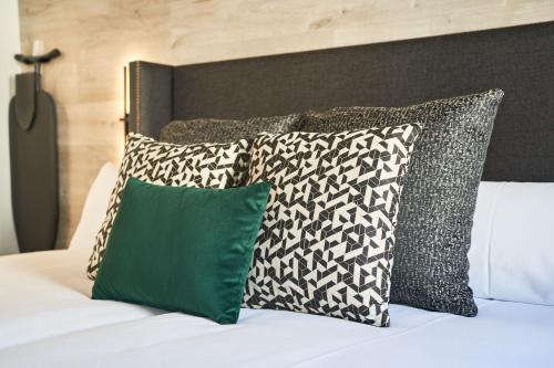 a bed with four pillows and a green pillow at Hotel Regina in Madrid