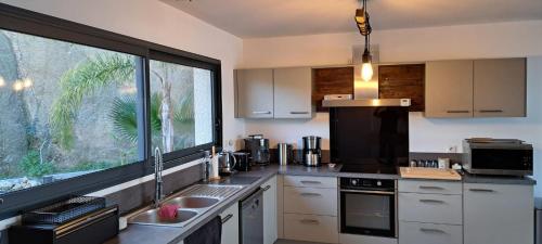 a kitchen with a sink and a large window at Villa de Luxe avec Piscine à débordement chauffée à Porticcio in Porticcio