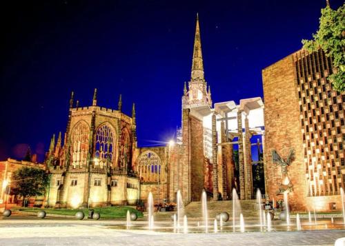 a large cathedral with a tall building with a steeple at La Maisón, City Centre House, EV Parking, Fast WiFi, Netflix Private Entrance, Garden in Coventry