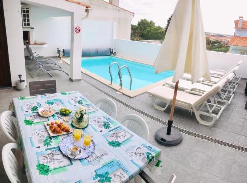 a table with food on it next to a swimming pool at Sunset Chateau -Piscina Aquecida, Vista Mar in Atouguia da Baleia