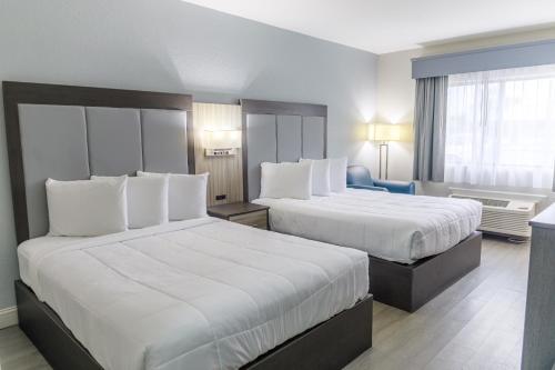 a hotel room with two beds with white sheets at Admiral's Inn on Tybee Island in Tybee Island