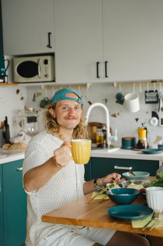 a woman sitting at a table holding a cup at Costa del Kryspi Całoroczne Domy na Wodzie in Cholerzyn