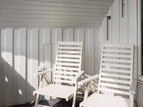 two white chairs sitting next to a fence at 4 star holiday home in Halmstad in Halmstad