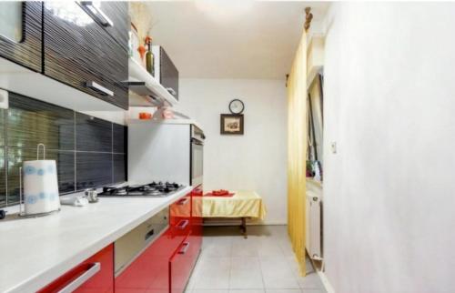 a kitchen with white counters and red cabinets at Slatka sobica za dvoje sa upotrebom zajednicke kuhinje i kupaonice in Zagreb
