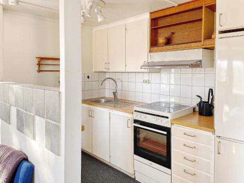 a kitchen with white cabinets and a sink and a stove at 4 person holiday home in HERRäNG-By Traum in Herräng