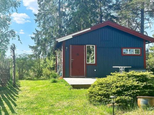 a blue house with a red door in a yard at 4 person holiday home in HERRäNG-By Traum in Herräng
