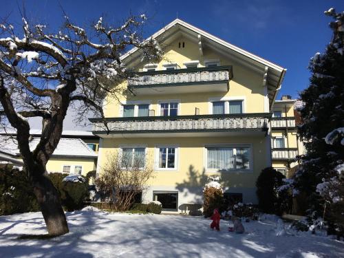 a large yellow house with a child in the snow at Pension & Apartments Ertl in Seeboden