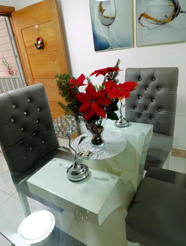 a glass table with a vase of red flowers on it at "comodidad, seguridad y cercano a todo" in Los Paredones