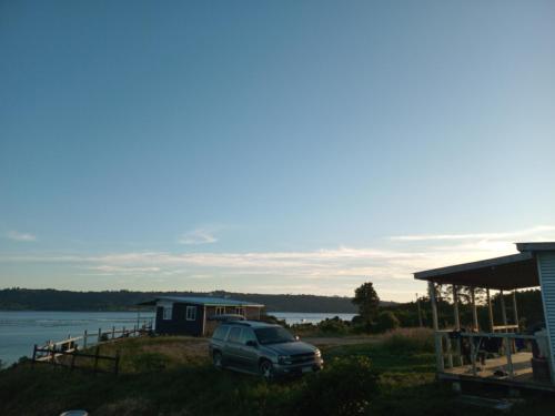 a car parked in front of a house and a lake at Dalcahue cabañas Lacuesta in San Javier