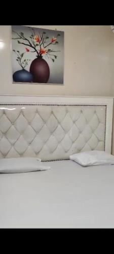 a white bed with two pictures on the wall at Familly fun in Dakar