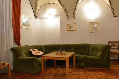 a living room with a green couch and a guitar at Hotel Gufo in Bormio