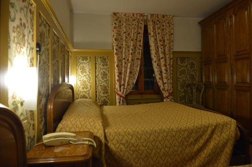 a bedroom with a bed with a phone on it at Hotel Gufo in Bormio