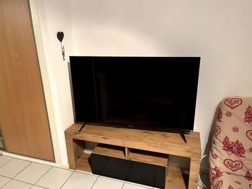 - une télévision à écran plat sur un support en bois à côté d'une porte dans l'établissement Studio du Lac, à Gérardmer
