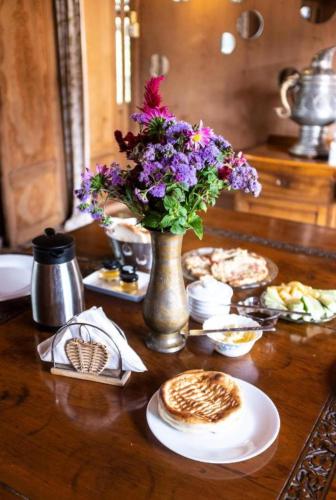 a table with a vase of flowers and some food at OMAR KHAYYAM HOUSEBOAT RETREAT and FAVELA HEADROOMS in Srinagar
