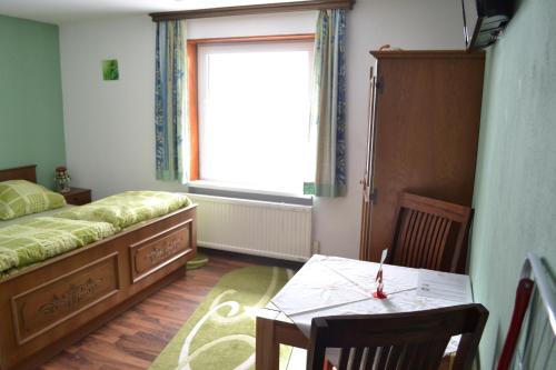 a bedroom with a bed and a table and a window at Pension Haus Rohrmoser in Annaberg im Lammertal