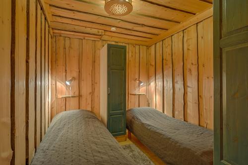 two beds in a room with wooden walls at VIP Rakka Villas 7 & 8 in Levi