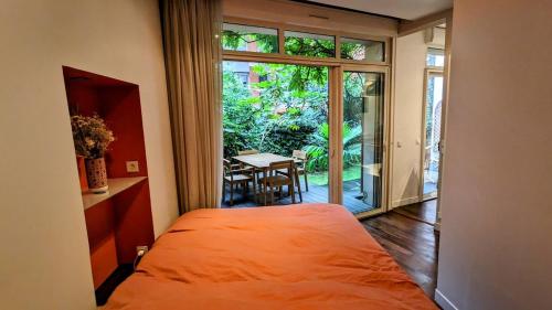 une chambre avec un lit et une table et une grande fenêtre dans l'établissement Beautiful apartment with private garden, à Paris