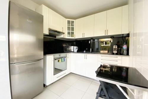 une cuisine avec des armoires blanches et un réfrigérateur en acier inoxydable dans l'établissement Appartement 3 pièces avec parking 8 people, à Saint-Ouen