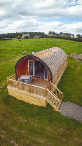 a round house with a deck in a field at Autumn Special Offer - Secluded Luxury Cabins with stream, stargazing, walks and nature - Fell Farm Hideaway in Colwell
