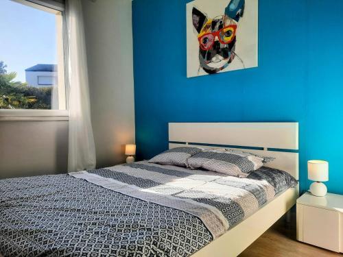 ein Schlafzimmer mit einem Bett mit einer blauen Wand in der Unterkunft Les Merisiers - Maison moderne avec jardin in Pornic