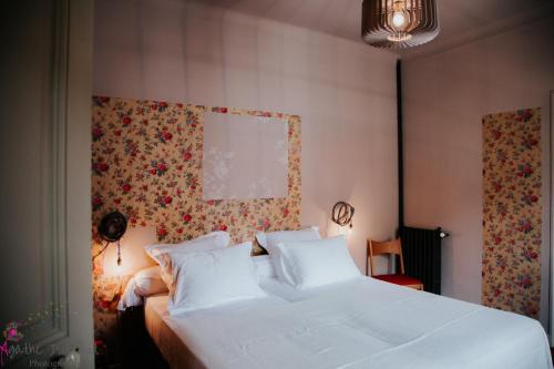 a bedroom with a white bed with a floral wall at Hôtel particulier des Jasmins in Le Bar-sur-Loup
