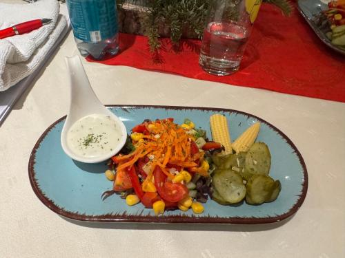 a plate of food with vegetables and a bowl of dip at Hotel-Restaurant Christine in Lübz