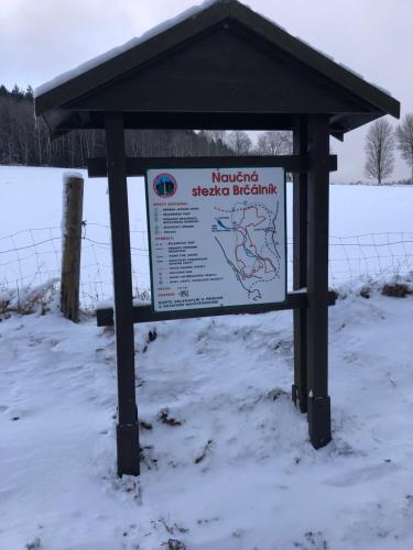 a sign in the snow next to a fence at Apartmán Borůvka in Železná Ruda