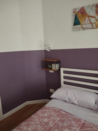 a bedroom with a bed with a purple wall at Unmei Home in Rome
