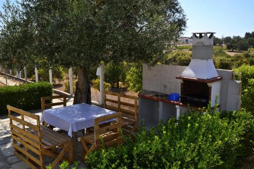 a table and chairs and an outdoor oven in a garden at Monte da Vinha Nova in Santiago do Cacém