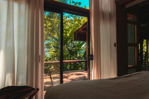 a bedroom with a bed and a sliding glass door at Casa Luz Paraty in Paraty