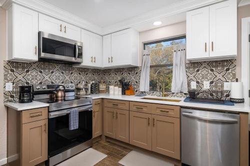 a kitchen with white cabinets and stainless steel appliances at Spacious 4BR Home with Pool BBQ & Games in Grand Prairie