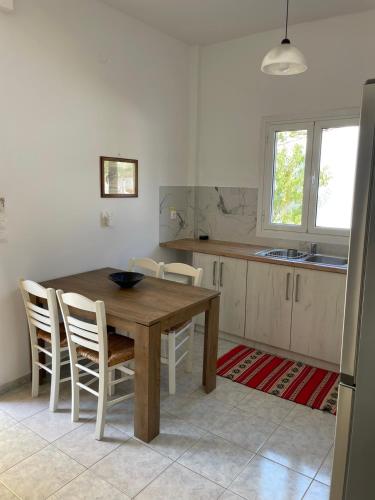 a kitchen with a wooden table and white chairs at NAFSIKA Apartments in Agios Georgios Pagon