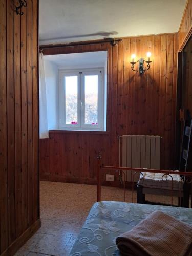 a bedroom with wooden walls and a window and a bed at LA BAITA di Ornaro Alto Rieti - oasi di pace tra Roma e Terminillo in Ornaro