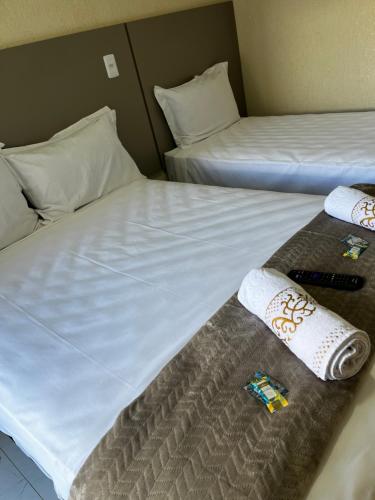 two beds in a hotel room with towels on them at Hotel Aris in União da Vitória