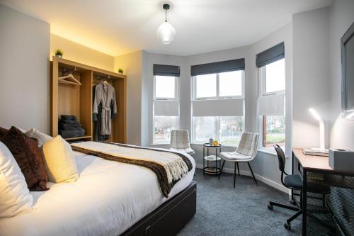 a bedroom with a bed and a desk and windows at Entire Luxurious 2 Bedroom Flat in Leicester